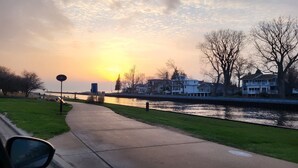 Ein Uferweg mit freiem Blick auf Häuser und einen Sonnenuntergang.