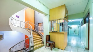 A hotel lobby with a spiral staircase, a wooden reception desk, and a chair. - Sislink Suites (Nairobi)