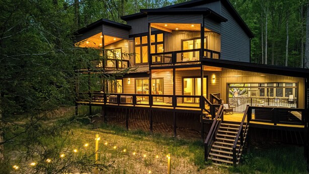 A two-story wooden cabin with a deck, a fire pit, and outdoor seating.