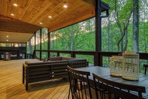 Une terrasse extérieure couverte, dotée d’un plancher en bois, de sièges et de tables.