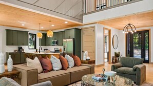 A spacious living area with a sofa, armchairs, and a coffee table. A kitchen with modern appliances and a dining area with a table and chairs are visible.