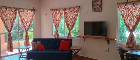 A living room with a sofa, TV, and dining area.