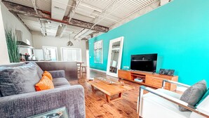 Een moderne woonkamer met een blauwgroene accentmuur, houten vloeren en moderne meubels.