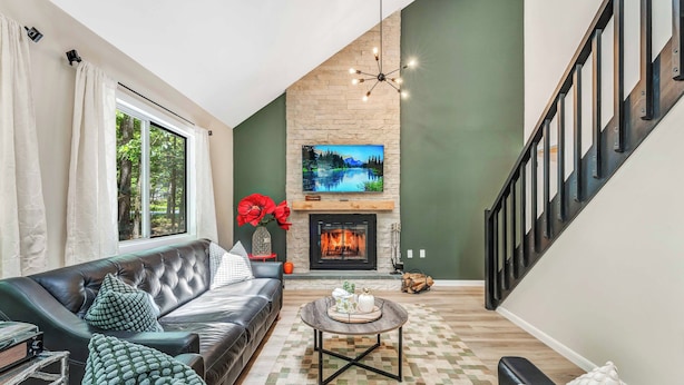 A living room with a fireplace, a sofa, a coffee table, and a staircase.