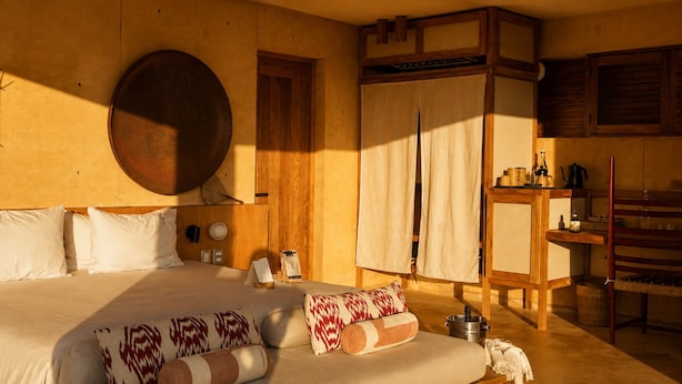 Un dormitorio con una cama grande, cabecera de madera y un armario de madera con utensilios de cocina.