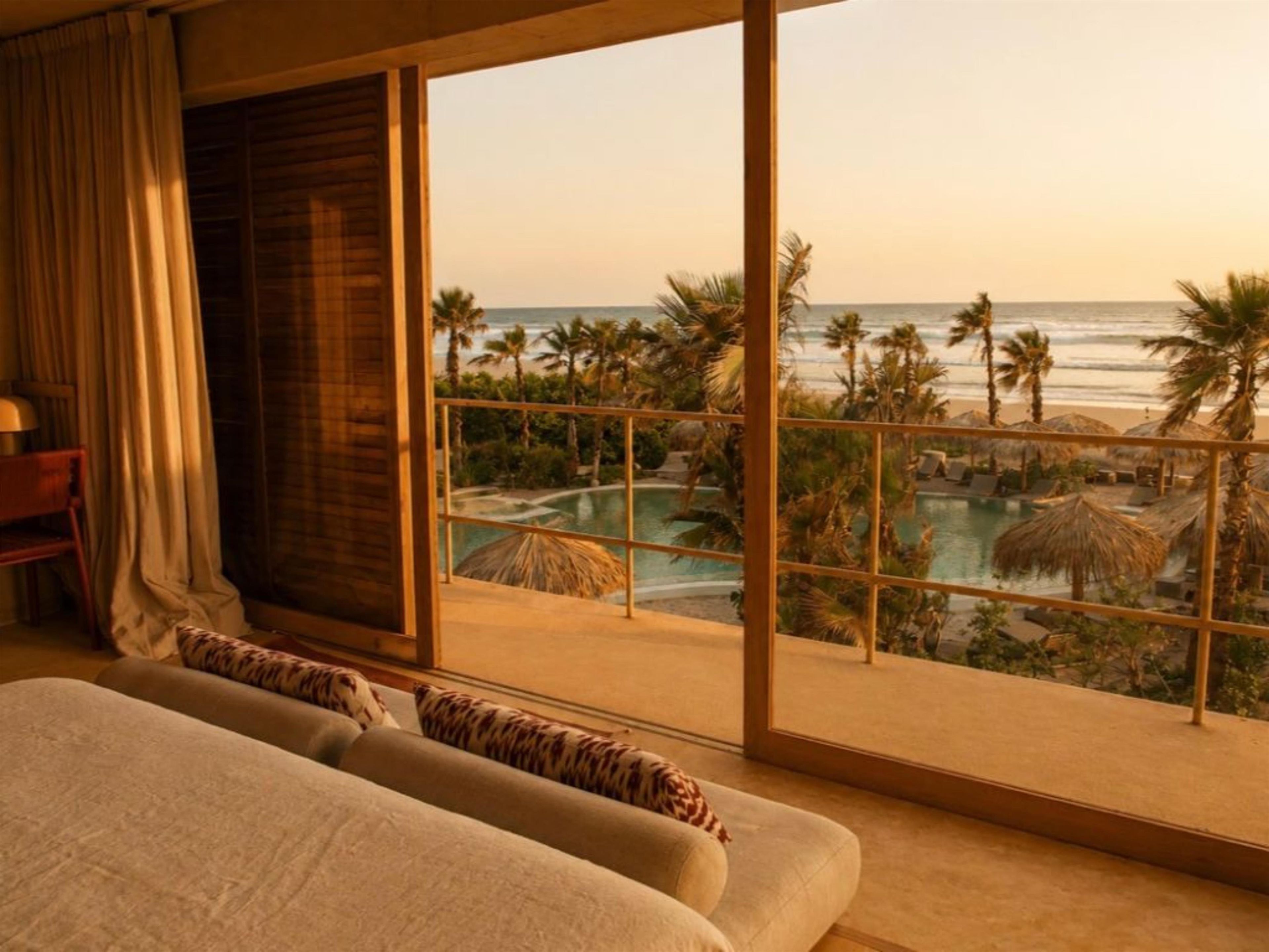 Un dormitorio con un ventanal grande con vistas a una piscina y una playa.