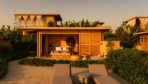 A modern resort with a spacious outdoor seating area, a well-appointed bedroom, and lush tropical vegetation.