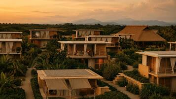 Un resort con varias edificaciones de madera, algunas con balcones, rodeado de exuberante follaje y un telón de fondo montañoso.