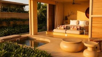 A modern outdoor seating area with a pool, a sofa with patterned cushions, and a wooden table.