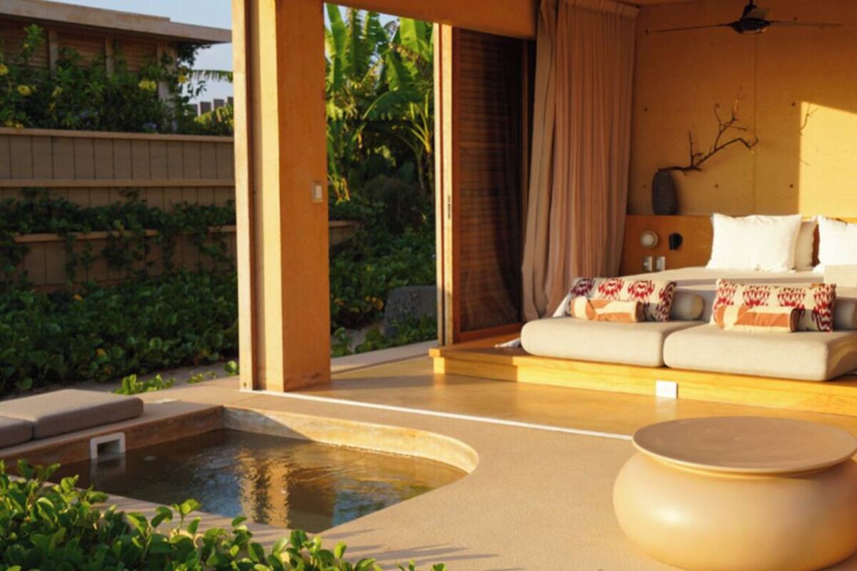 Une chambre moderne avec un grand lit, un petit canapé, un plancher en bois et une petite piscine.