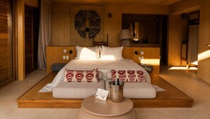 Un dormitorio espacioso con una cama grande, una mesita de noche con lámpara y un espejo en la pared.