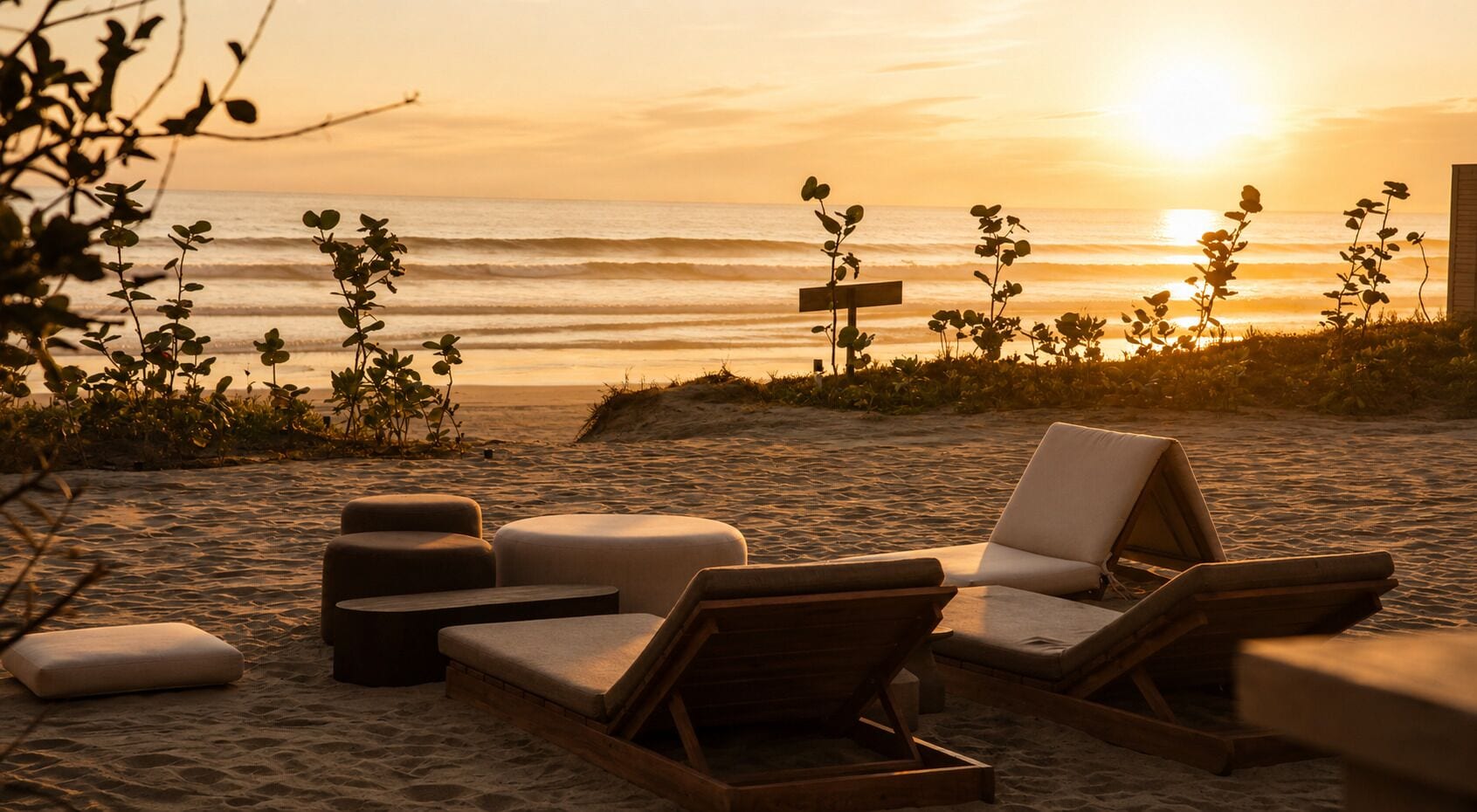 Una playa con sillas de descanso y un cartel de madera.