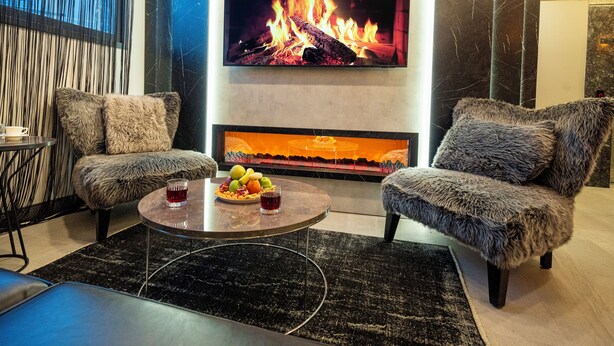 A modern living room with a fireplace, a flat-screen TV, and a cozy seating area.