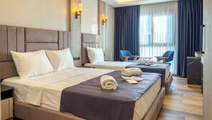 A modern hotel room with a large bed, bedside tables, a desk, and a seating area with chairs.