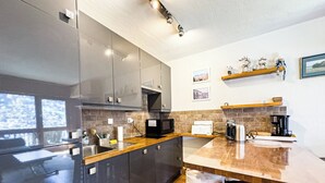 A modern kitchen with a wooden countertop, stainless steel appliances, and a bar stool. - Apartment with mountain view in Saint-Gervais (Saint-Gervais-les-Bains)