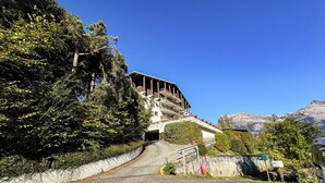 A building with a sloped roof, a staircase leading to a covered area, and a mountain in the background. - Apartment with mountain view in Saint-Gervais (Saint-Gervais-les-Bains)