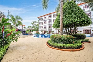 A hotel courtyard with a swimming pool, lounge chairs, and a well-maintained garden. - La Paloma Blanca B4 (Jaco Beach)