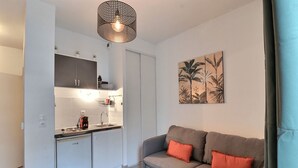 A compact living space with a kitchenette, a sofa with cushions, and a wall-mounted artwork. - Lovely apartment for 2 in Marseille (Marseille)
