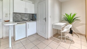 A compact kitchen with white cabinets, a marble backsplash, and a small sink. There's a white chair and a potted plant in the corner. - Apartment - 4P -  Villeurbanne (Villeurbanne)