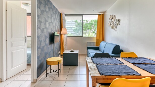 A modern living room with a sofa, a dining table with chairs, a TV, and a window with curtains. - Apartment - 4P -  Villeurbanne (Villeurbanne)