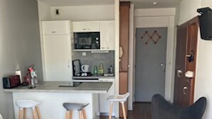 A compact living space with a kitchenette, a dining area with stools, a sofa, and a black chair. - Charming apartment 20 m from the beach in Arcachon (Arcachon)