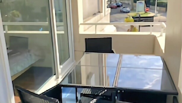 A compact balcony with a glass table and chairs, overlooking a street with parked cars and greenery. - Charming apartment 20 m from the beach in Arcachon (Arcachon)