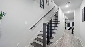 Un escalier moderne avec une rampe en métal, des murs blancs et un plancher en bois.