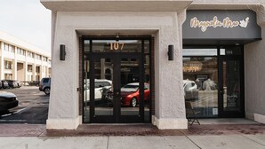 A boutique hotel entrance with a glass door, numbered 107, and a sign reading "Magnolia Mae Boutique".