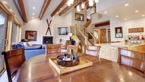 A spacious living room with a wooden dining table, a fireplace, and a kitchen area with a wooden island. - PG305 Beautiful Copper Getaway! (Frisco)