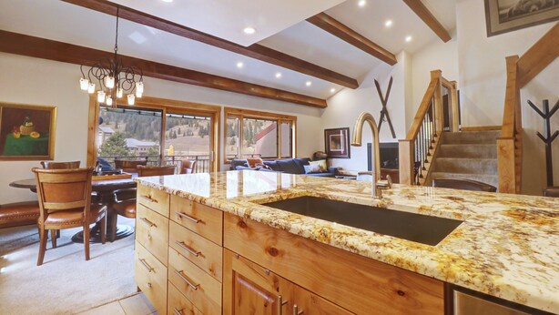 A spacious kitchen with a large island, wooden cabinetry, and a view of the outdoors through large windows. - PG305 Beautiful Copper Getaway! (Frisco)