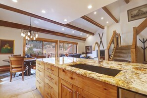 Una cocina amplia con una isla grande, armarios de madera y vistas al exterior a través de amplios ventanales.