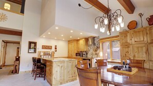 A spacious kitchen with wooden cabinets, a central island, and a dining area with a large table and chairs. - PG305 Beautiful Copper Getaway! (Frisco)