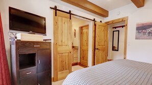 A bedroom with a large bed, a TV mounted on a wooden cabinet, and a sliding barn door closet. - PG305 Beautiful Copper Getaway! (Frisco)