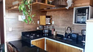 Une cuisine moderne avec des meubles en bois, un plan de travail noir, une cuisinière à gaz, un évier et un four à micro-ondes.