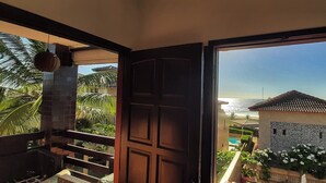 Un balcon avec vue sur la mer et un bâtiment aux tuiles apparentes.