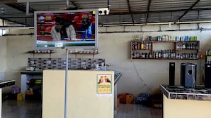 Un bar amb televisió que mostra un combat de boxa, prestatges amb diverses begudes i un sòl de rajola.