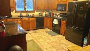 A kitchen with wooden cabinets, a black refrigerator, and a microwave.