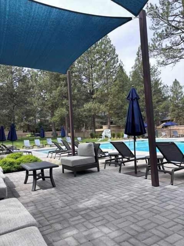 A poolside area with lounge chairs, umbrellas, and a pool.
