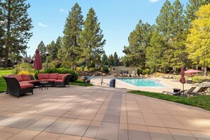 A pool area with lounge chairs, a hot tub, and a seating area with a sofa and chairs.