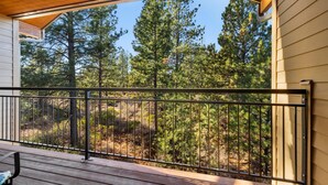 A wooden deck with a metal railing overlooking a forested area. - 10 Min to Mt Bachelor Mountain View Sleeps 6 (Bend)