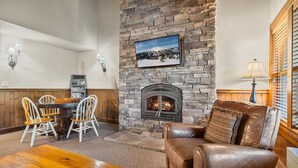 A cozy living room with a stone fireplace, a wooden dining table with chairs, and a leather sofa. - 10 Min to Mt Bachelor Mountain View Sleeps 6 (Bend)