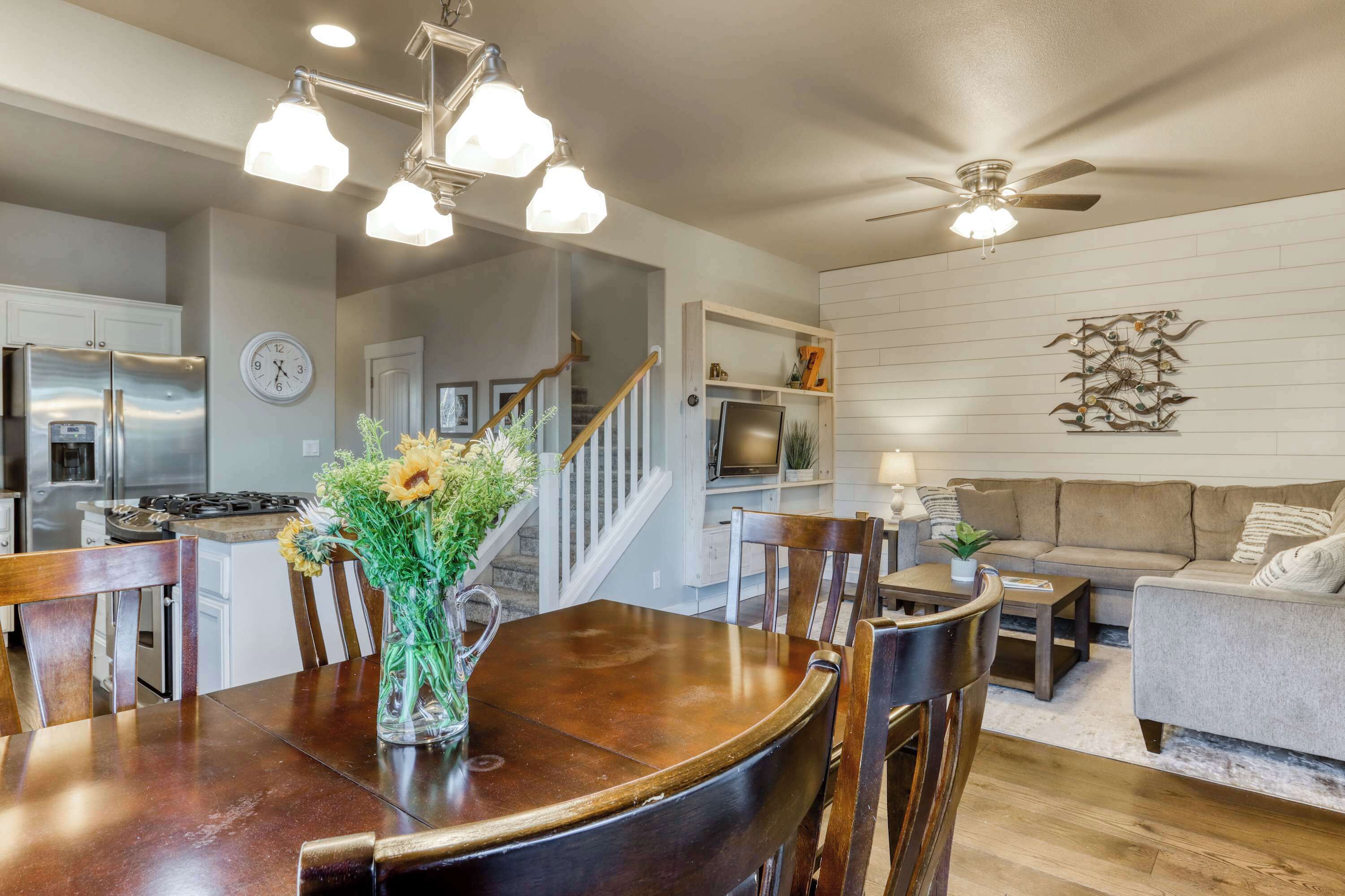 A modern kitchen with a dining area, a staircase, and a living room with a sofa and coffee table.