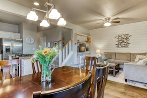 A modern kitchen with a dining area, a staircase, and a living room with a sofa and coffee table.