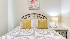 A neatly made bed with striped bedding and two pillows, a bedside lamp, and a floral artwork on the wall. - 4BR Bend Home Near Mt Bachelor and River Trails (Bend)