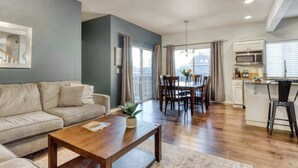 A modern living room with a sofa, coffee table, and dining area with chairs and a table. - 4BR Bend Home Near Mt Bachelor and River Trails (Bend)
