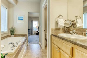 A bathroom with a bathtub, a sink, and a mirror. There is a towel rack above the sink and a framed picture on the wall. - 4BR Bend Home Near Mt Bachelor and River Trails (Bend)
