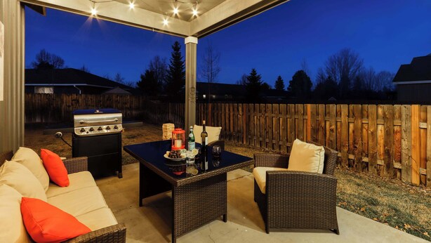 An outdoor patio with wicker furniture, a barbecue grill, and a table set for dining. - 4BR Bend Home Near Mt Bachelor and River Trails (Bend)