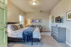 A bedroom with a bed, a dresser, a chair, and a television on the wall.
