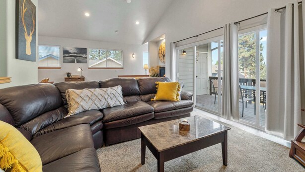 A spacious living room with a leather sectional sofa, a coffee table, and a large window with a view of the outdoors.