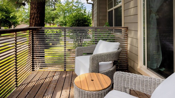 Eine Holzterrasse mit Korbmöbeln und einer Glastür.